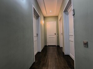 A hallway with a wooden floor, white doors, and a light switch on the wall. - Fortuna Boutique Hotel & Restaurant (Gabala)