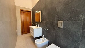 A modern bathroom with a bidet, toilet, and a vanity with a mirror. - Civico 53 Apartments (Avola)