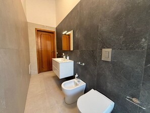 Ein modernes Badezimmer mit einer Bidet, Toilette und einem Waschtisch mit Spiegel.