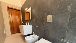 A modern bathroom with a bidet, toilet, and vanity. - Civico 53 Apartments (Avola)