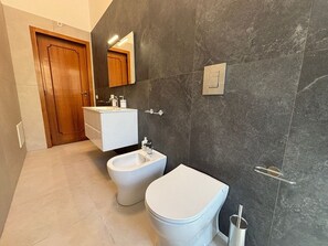A modern bathroom with a bidet, toilet, and vanity. - Civico 53 Apartments (Avola)