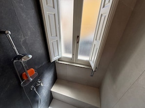 Ein Badezimmer mit Dusche, Fenster und Handtuchhalter.