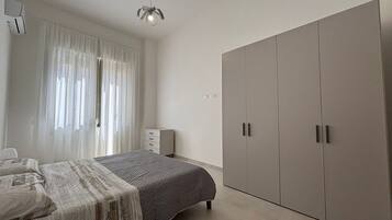 Una camera da letto con un letto, un armadio, un comodino e una finestra con tende.