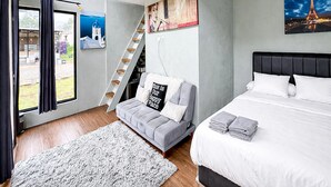 Un dormitorio con cama, sofá, escalera y vistas a la Torre Eiffel.