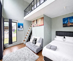 A bedroom with a bed, a sofa, a staircase, and a view of the Eiffel Tower. - Cozzy Talaga Artea Pangalengan (bandung)