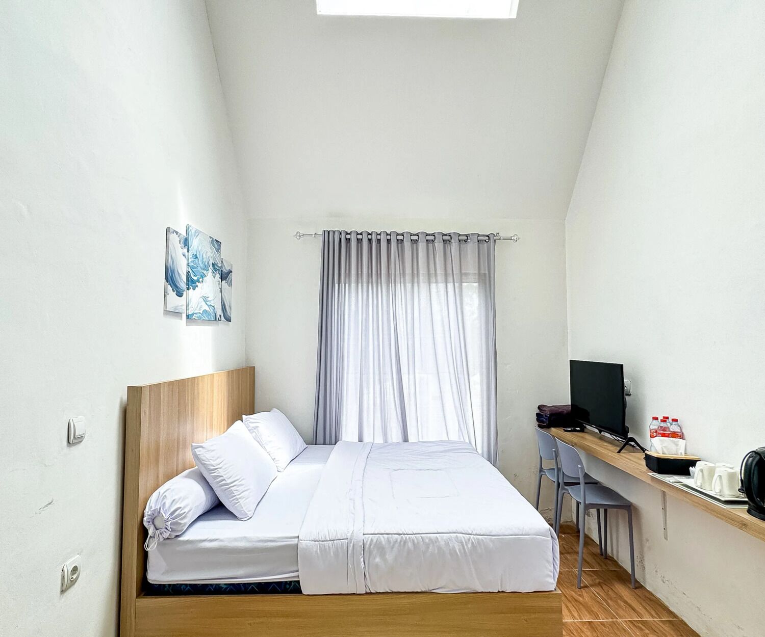 A bedroom with a bed, a desk with a computer, and a window with curtains.
