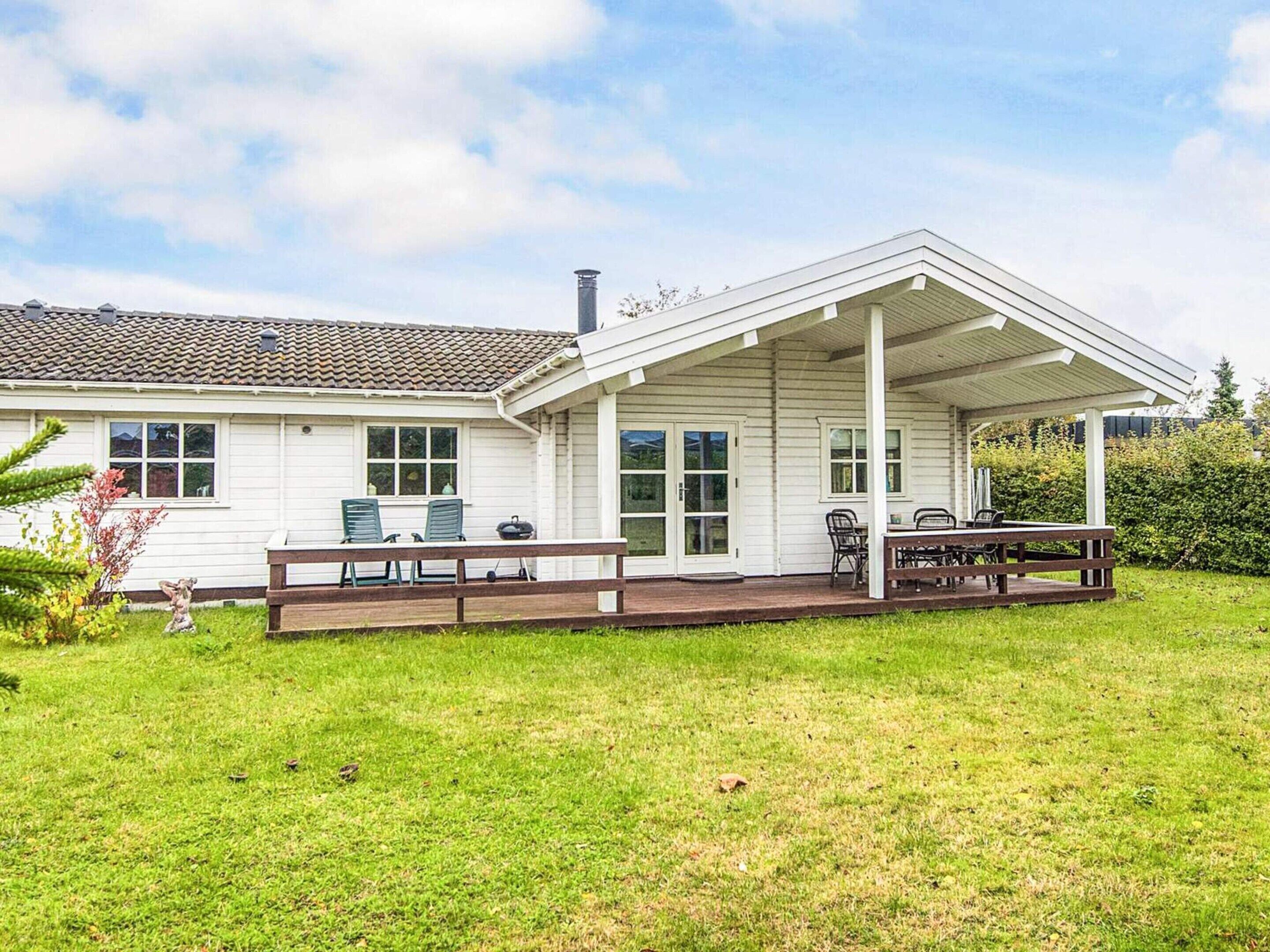 A white house with a covered patio and a grassy yard.