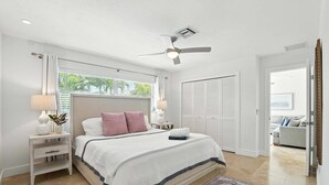 Een slaapkamer met een bed, nachtkastjes, een plafondventilator en uitzicht op de omgeving.