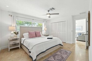 Ein Schlafzimmer mit einem Bett, Nachttischen, einem Deckenventilator und Blick ins Freie.