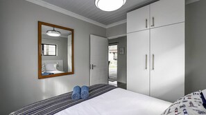 A bedroom with a bed, a mirror, a wardrobe, and a door leading to an outdoor area.