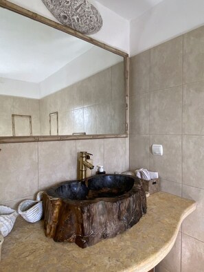 Un baño con un espejo grande, un lavabo de madera y un perchero para toallas.