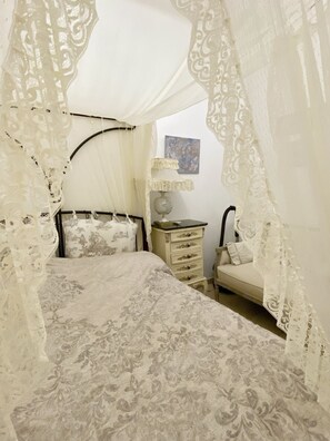A bedroom with a canopy bed, a nightstand, a lamp, and a small table. - Mykonos Cycladic house
The perfect White House , near panormos beach (Mykonos)