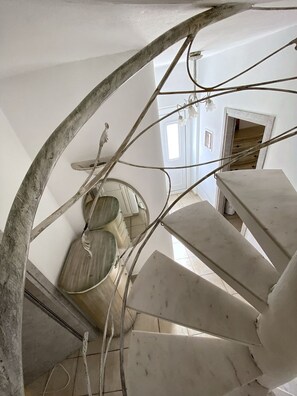 A spiral staircase with a rustic design, leading to a room with a large window and a door. - Mykonos Cycladic house
The perfect White House , near panormos beach (Mykonos)