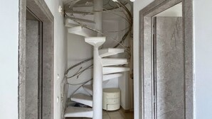 Una escalera en espiral con barandillas blancas y un candelabro con flores blancas.