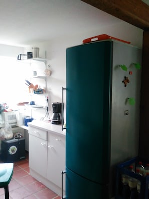 A kitchen with a refrigerator, microwave, and coffee maker.