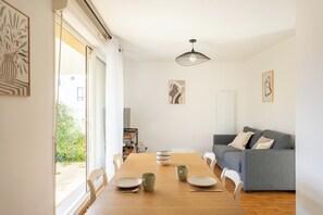 En matplats med ett träbord, stolar, en grå soffa och konstverk på väggarna.