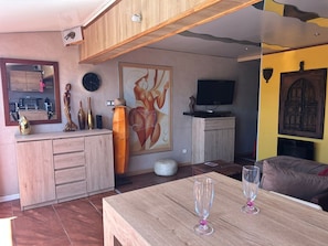 Ein modernes Wohnzimmer mit einem Holzespeisetisch, einem Fernseher und einem großen abstrakten Gemälde.
