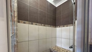 Een douche met betegelde wanden en een stenen plank.