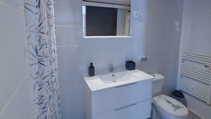 A bathroom with a white sink, mirror, and toilet.