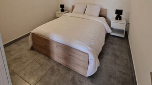 A bedroom with a bed, nightstands, and a wall-mounted light fixture.