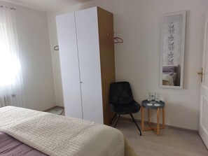 A bedroom with a bed, a wardrobe, a chair, a small table with a glass, and a framed picture on the wall. - Cozy vacation apartment for 2-4 persons (Engelskirchen)