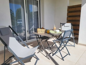 A balcony with a table, chairs, and a basket of bread. - Comfortable T2 apartment with swimming pool and beach within walking distance (Linguizzetta)