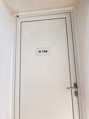 A white door with a sign reading 'N°184' and a door handle. - Comfortable T2 apartment with swimming pool and beach within walking distance (Linguizzetta)