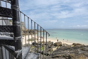 A coastal view with a staircase leading to a beach, rocky terrain, and clear skies. - Mermaids 2 - Sea views, direct beach access (St Ives)