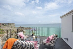 A balcony with outdoor seating, a view of the sea, and a stone wall. - Mermaids 3 - Sea-facing property, direct beach access (St Ives)