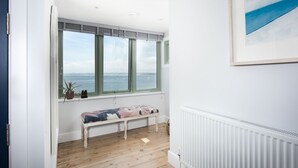 Ein Zimmer mit einer Bank, einer Heizung und einem großen Fenster mit Meerblick.