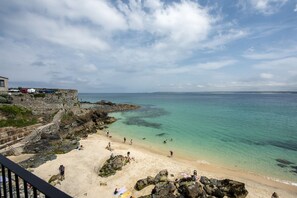 A coastal beach with clear turquoise waters, rocky shoreline, and a stone staircase leading down to the beach. - Mermaids - Sea-facing properties, direct beach access (St Ives)