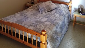 Un dormitorio con cama de madera, mesita de noche, lámpara y ventana.