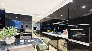 A modern kitchen with a marble countertop, black cabinets, and a dining area with a table and chairs. - Contemporary Designer Islington House (Greater London)