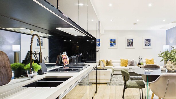 A modern kitchen with a central island, a dining area with a round table, and a living room with a sofa and cushions. - Contemporary Designer Islington House (Greater London)