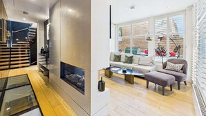A modern living room with a fireplace, a sofa set, a coffee table, and a view of the city through large windows. - Contemporary Designer Islington House (Greater London)