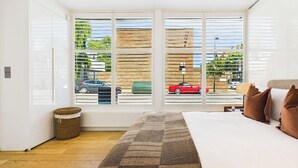 A bedroom with a large window, a bed, and a view of the street outside. - Contemporary Designer Islington House (Greater London)