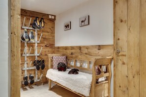 A wooden bench with a fluffy white cushion, a shoe rack with various types of shoes, and two framed animal pictures on the wall. - Chalet La Bouclia - Luxury Alpine retreat (Val-d'Isère)