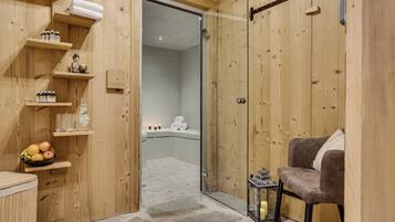 A wooden interior with a shower area, a chair, and shelves with toiletries.