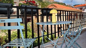A balcony with a table and chairs, a yellow lamp, and red flowers. - In the heart of Nafpaktos's city center, 50m from the sea and 5' from the port. (Nafpaktos)