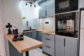 Eine moderne Küche mit Holztisch, grauen Schränken, einem schwarzen Backofen und einer Mikrowelle.