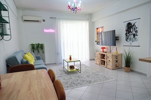 Ein Wohnzimmer mit einer Couch, einem Couchtisch, einem Fernseher und einer Deckenleuchte.
