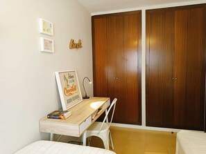 A bedroom with a wooden desk, a chair, a bed, and a wardrobe. - Beachfront Apartment with Sea-View Terrace (Calafell)