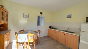 Eine Küche mit Esstisch, Stühlen, Schränken, einem Kühlschrank und einem Fenster.