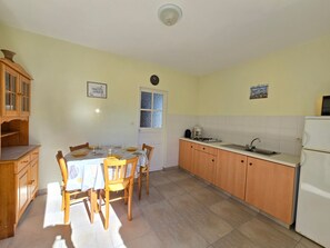 Eine Küche mit Esstisch, Stühlen, Schränken, einem Kühlschrank und einem Fenster.