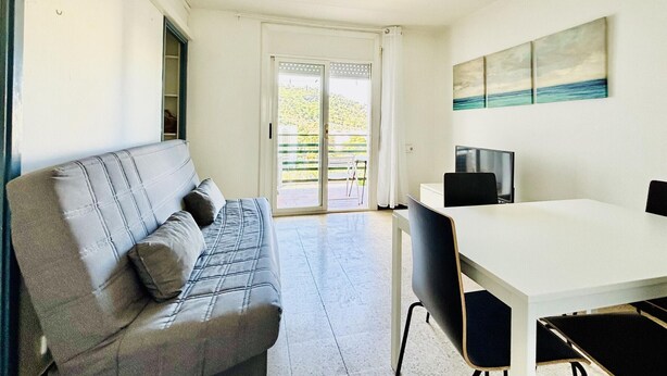 Une pièce comprenant un canapé, un téléviseur, une table et une porte-fenêtre coulissante donnant sur un espace extérieur.