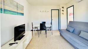 Un espace de vie compact comprenant un téléviseur, une table à manger et un canapé.