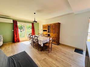 Ein Essbereich mit Tisch und Stühlen, einem Holzschrank und einer Glastür, die auf einen Balkon führt.