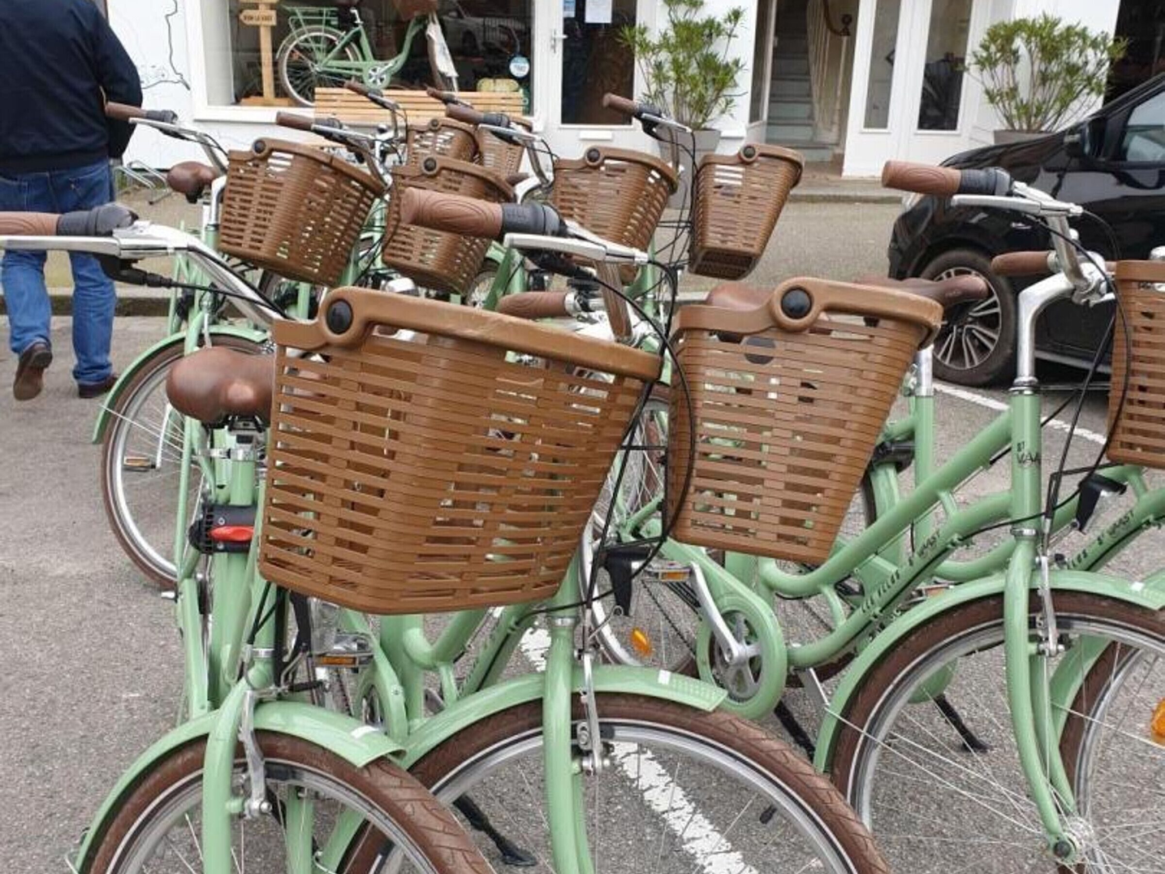 A row of vintage bicycles with wicker baskets, parked in a line.