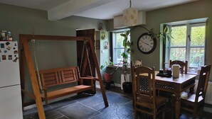 Una cocina con un columpio de madera, una mesa de comedor con sillas, un reloj y plantas en macetas.