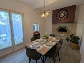 A dining area with a table set for four, a stone fireplace, and a wall clock. - Country house, pets welcome - 6 guests (Tavers)